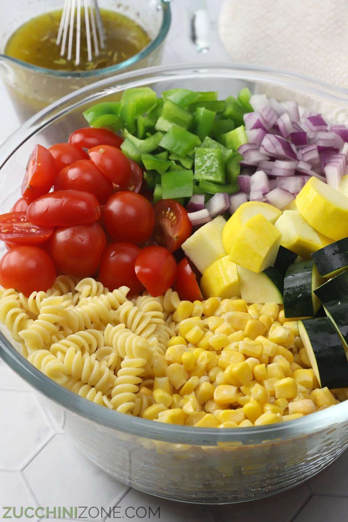 Pasta salad ingredients in a glass bowl.