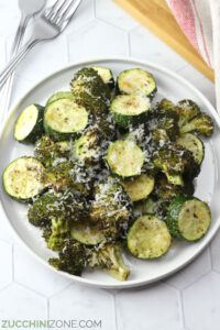 A white plate filled with roasted zucchini and broccoli.