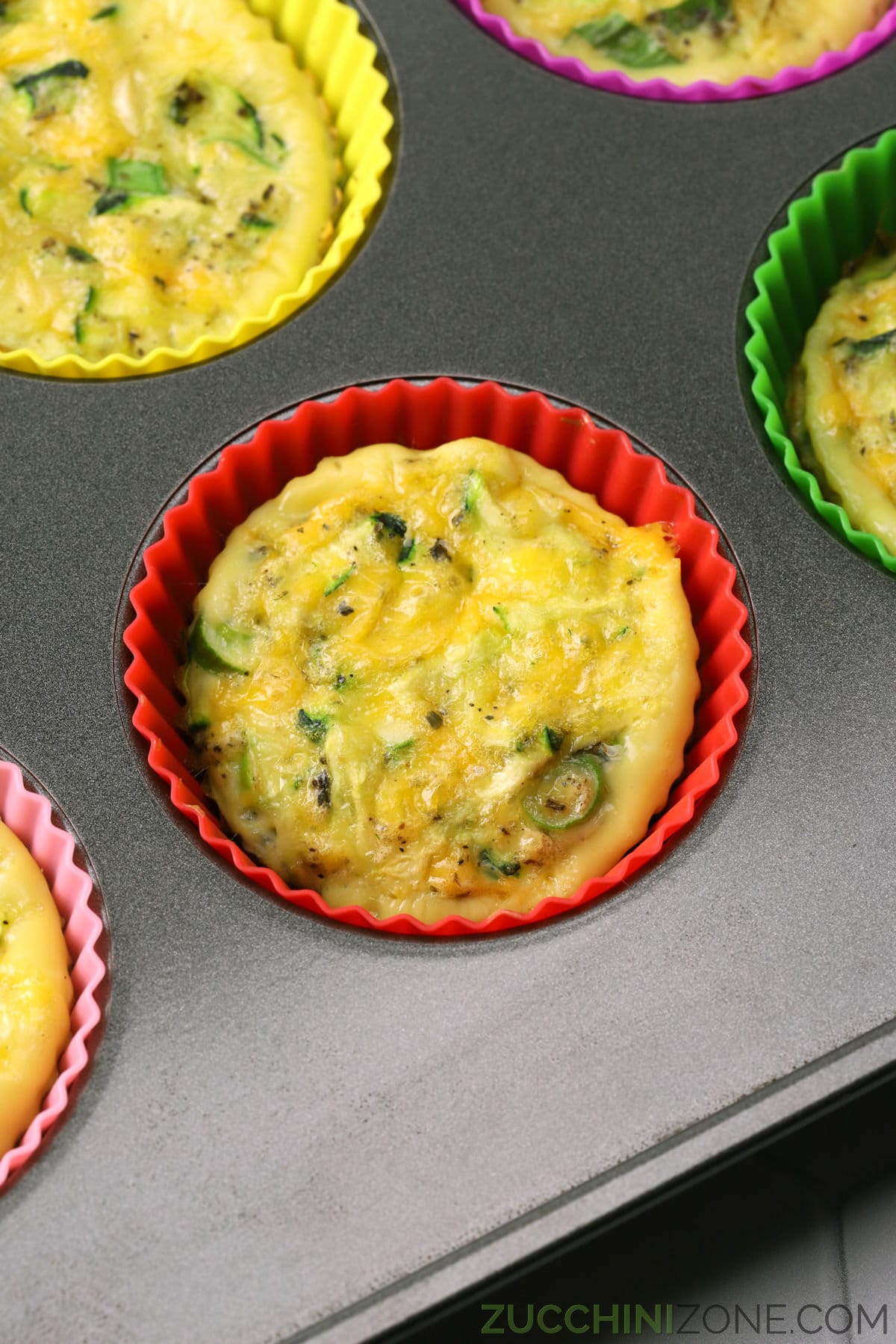 Zucchini egg muffins in silicone muffin liners in a pan.
