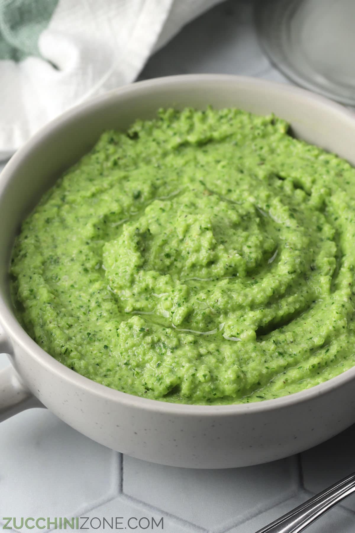 Taupe colored bowl filled with green zucchini pesto.