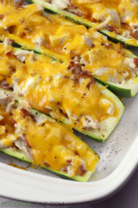 Close up of melty cheddar cheese on top of chicken zucchini boats.