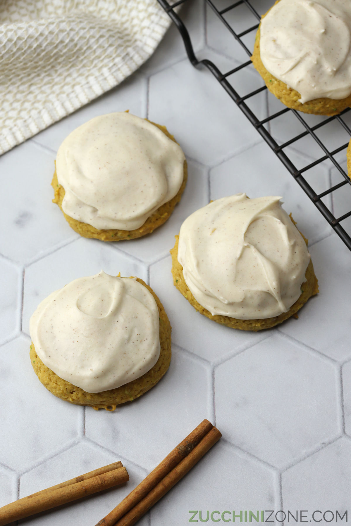 Frosted pumpkin zucchini cookies on a counter top.