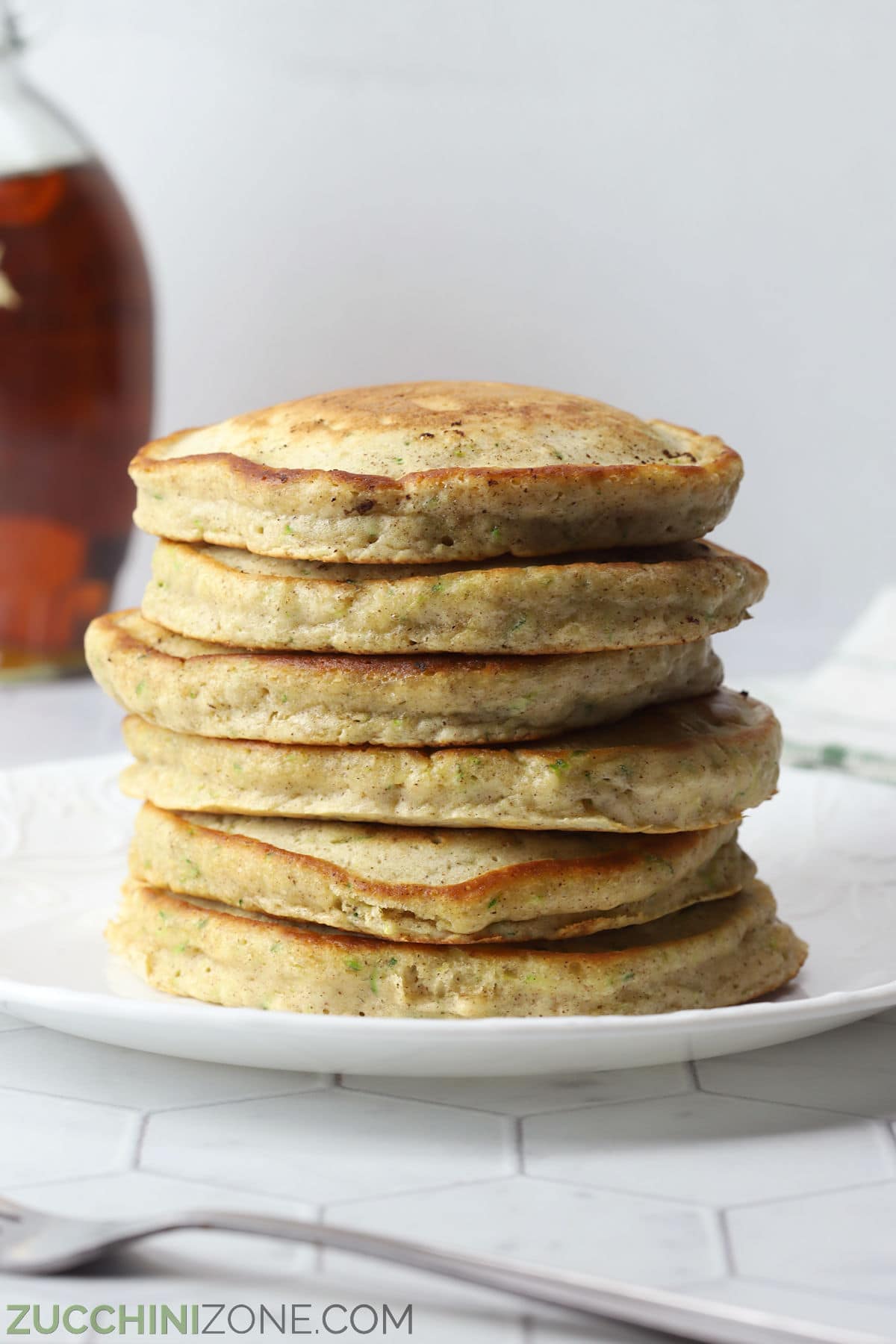 A stack of zucchini breakfast pancakes on a white plate.