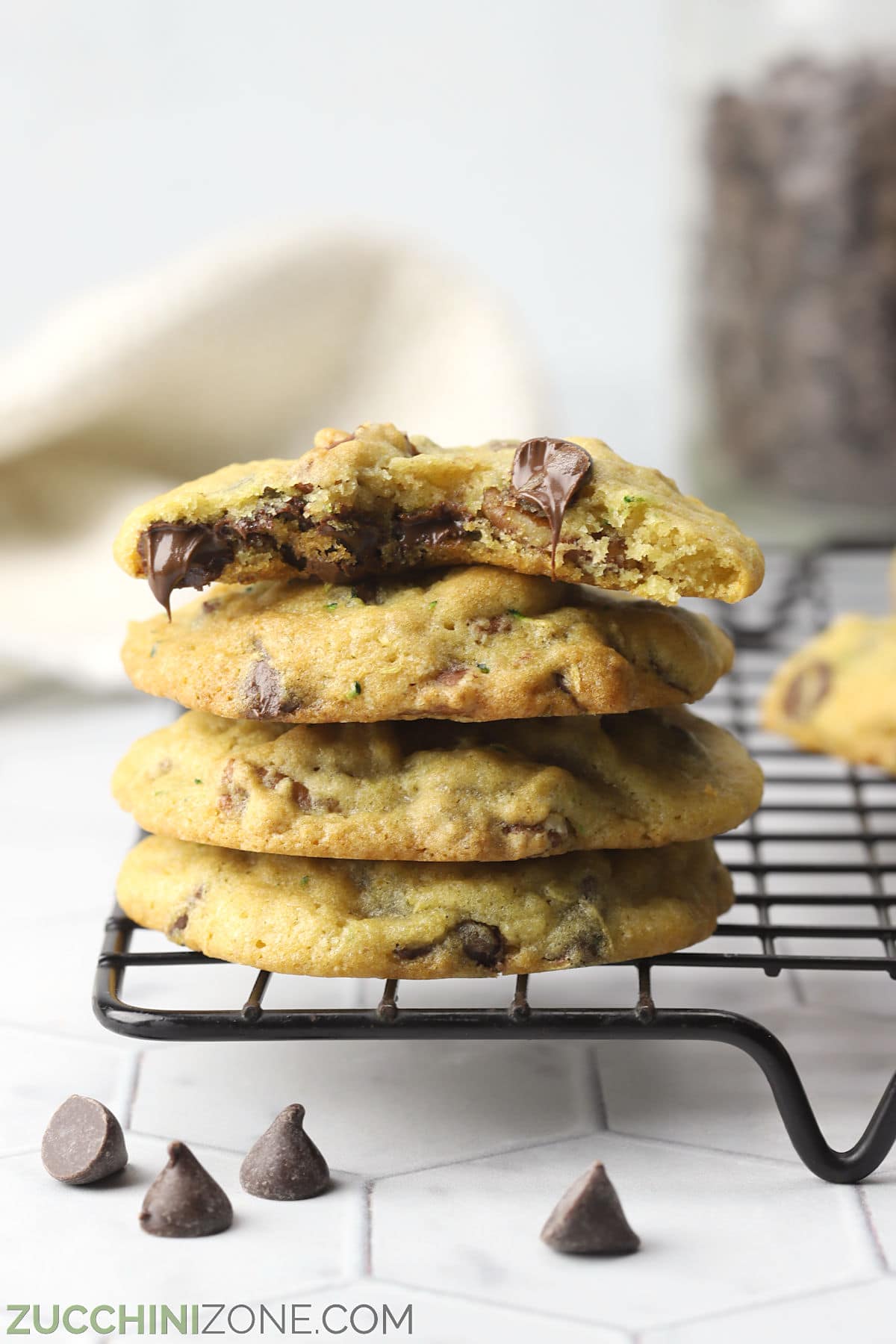 Chocolate chip pecan cookies stacked on a cookie cooling rack.