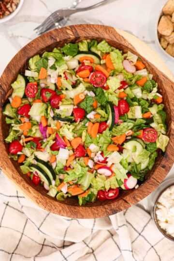 A wooden bowl of tossed salad.