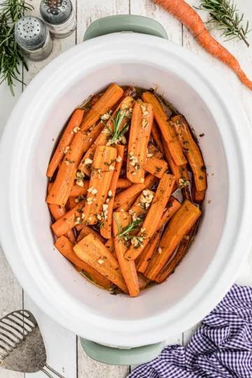 Sliced carrots topped with garlic in a slow cooker.