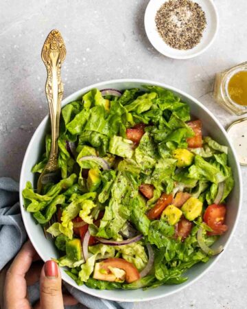 A bowl of salad with a serving fork.