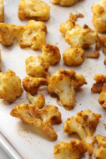 Roasted seasoned cauliflower on a sheet pan.