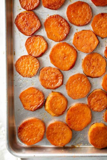 Round sweet potato slices on a metal sheet pan.