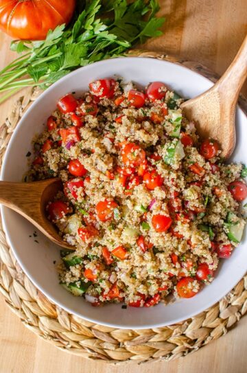 Summer quinoa salad in a serving bowl with wooden serving spoons.