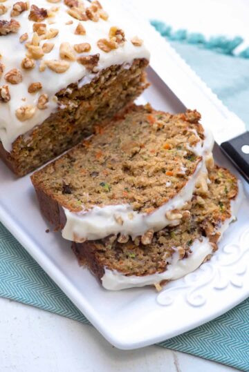 Sliced carrot zucchini bread loaf on a white platter.