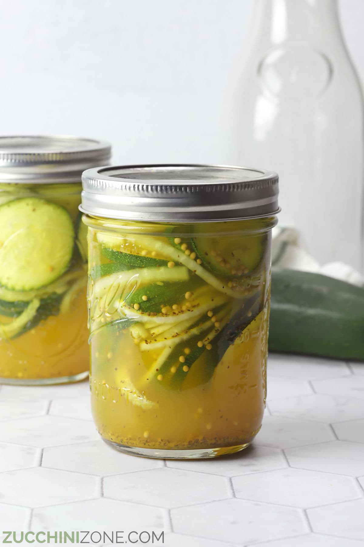 A jar of bread and butter zucchini pickles on a countertop.