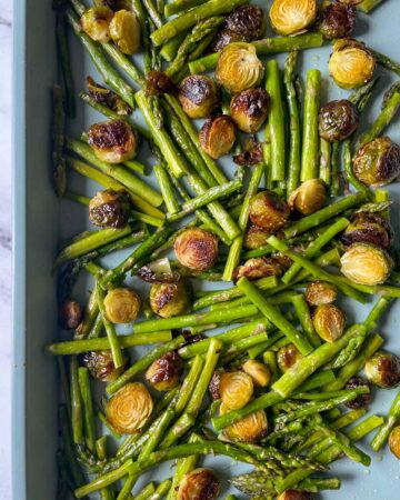 A roasting pan filled with brussels sprouts and asparagus.