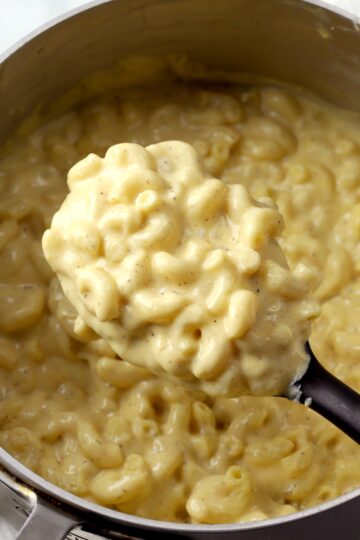 A pot of creamy mac and cheese with a wooden serving spoon.