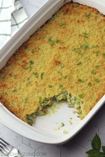 A white casserole dish filled with zucchini bake topped with panko crust.