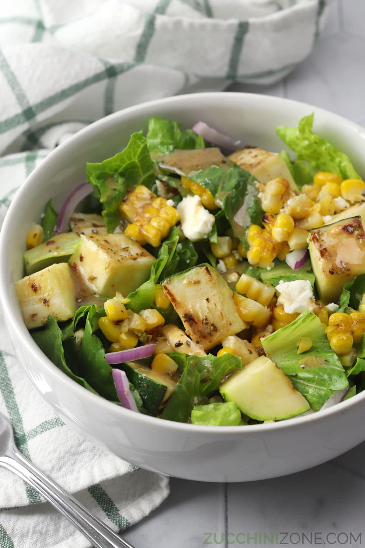 One serving of grilled zucchini salad in a white bowl.