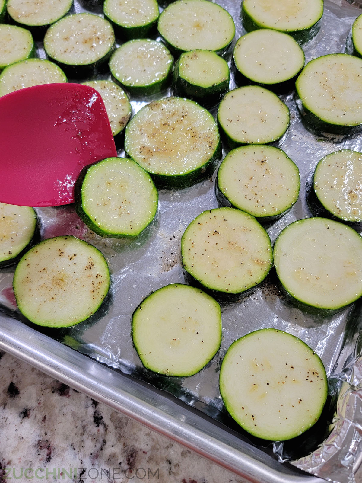 A metal sheet pan filled with thick slices of zucchini.