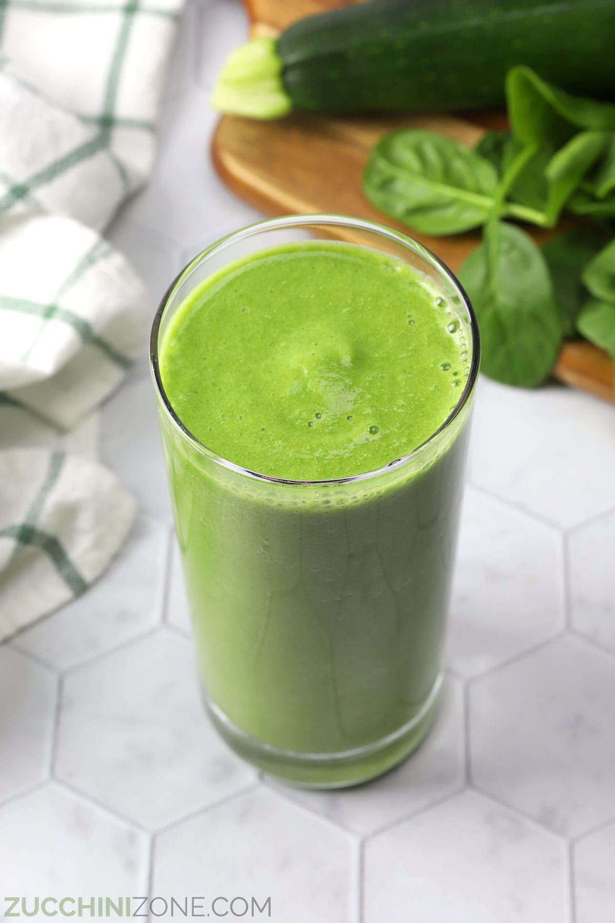 A tall glass filled with green apple smoothie.