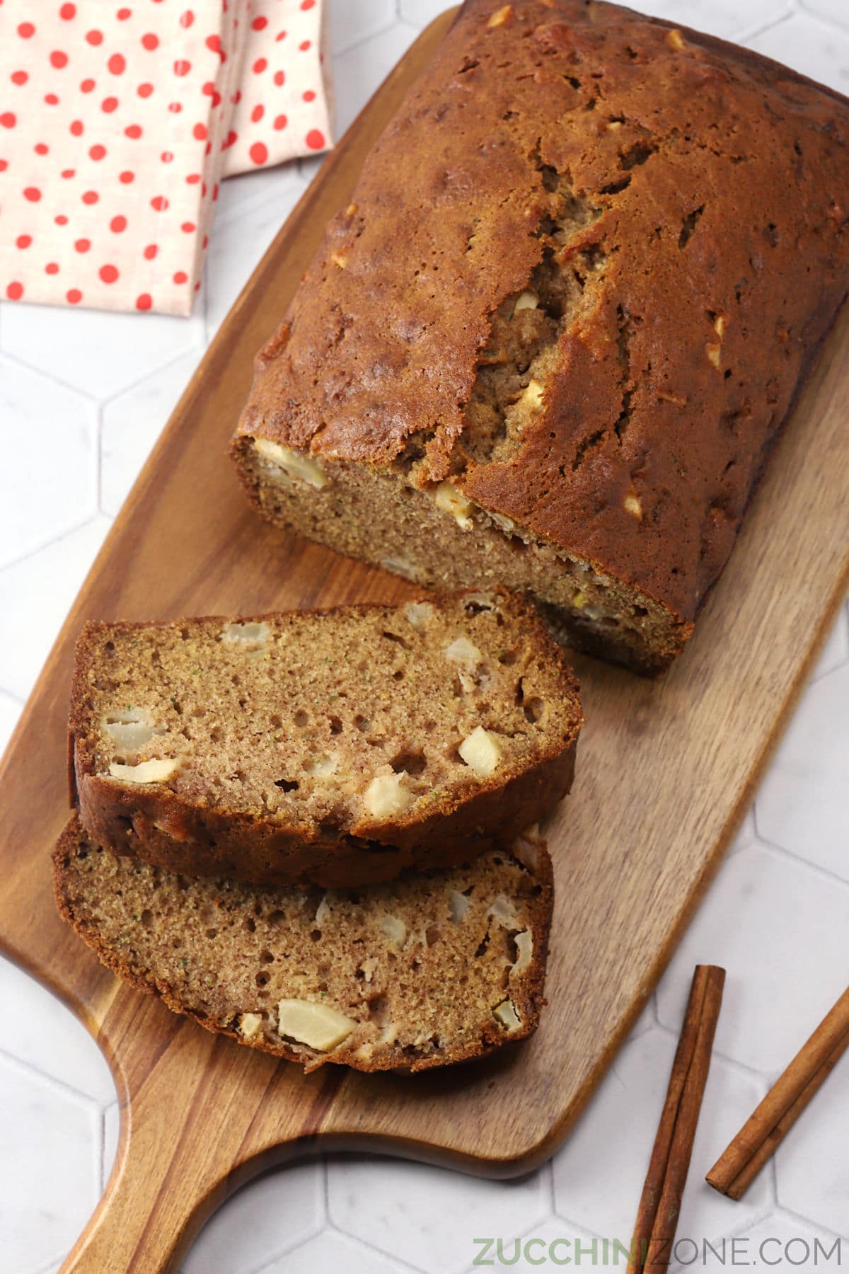 A loaf of apple zucchini bread on a wooden serving board.