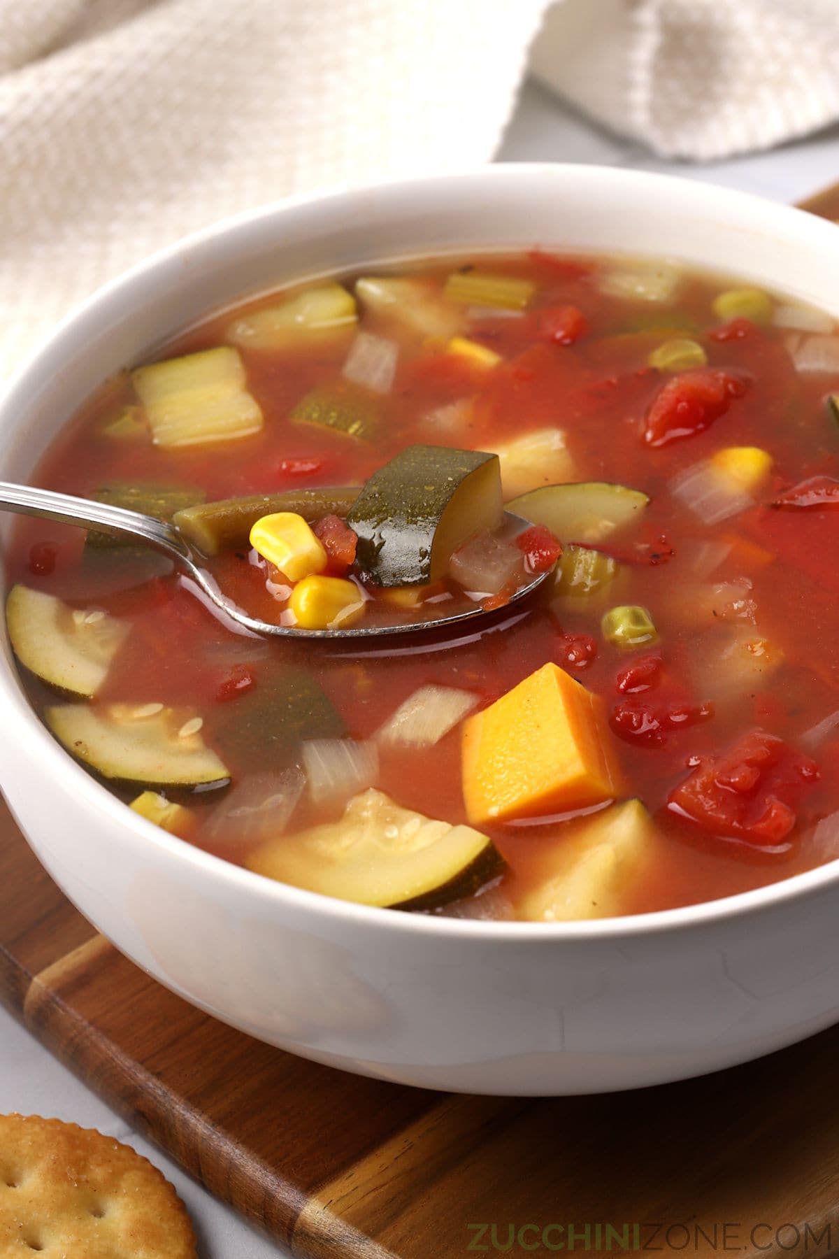 A metal spoon in a bowl of vegetable soup.