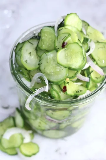 A glass jar of thinly sliced cucumber and onion.