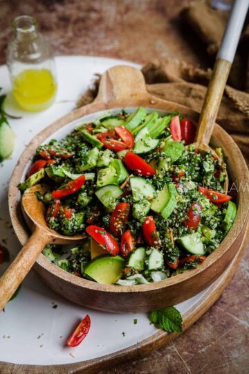 A wooden bowl of cucumber and tomato salad.