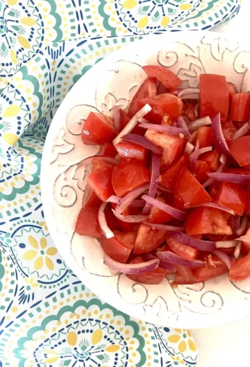 A white bowl of tomato and onion salad.