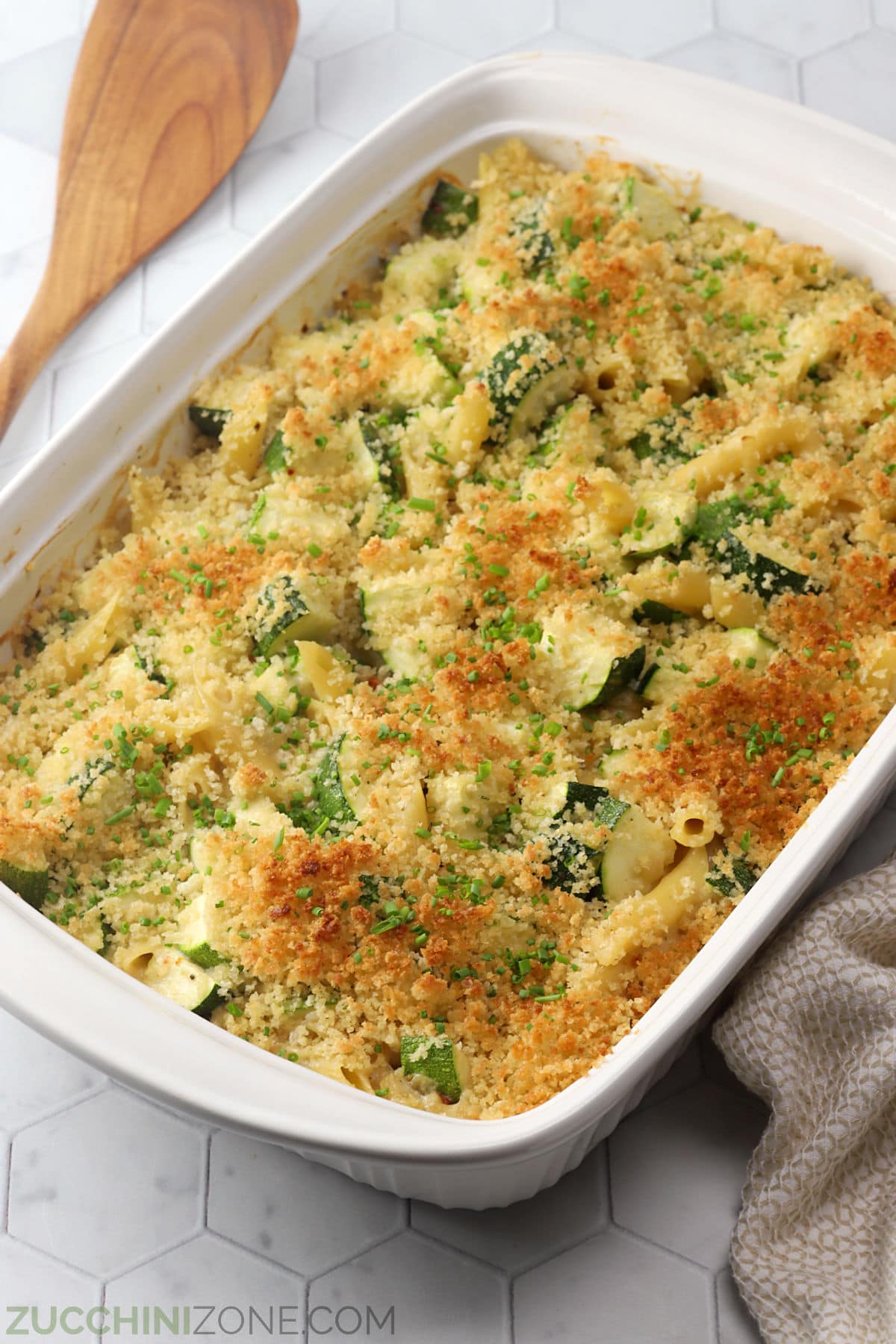 A white, 9x13 casserole dish filled with baked zucchini pasta.