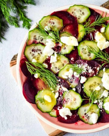 A white and pink bowl of beet and cucumber salad.