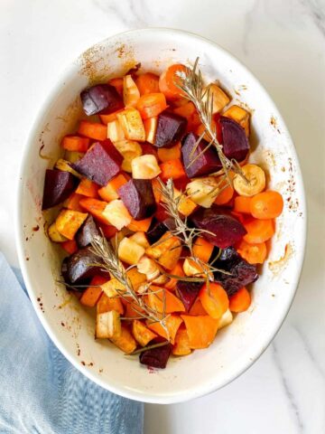 A white dish of honey roasted vegetables.