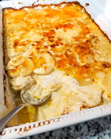 A white casserole dish of scalloped potatoes.