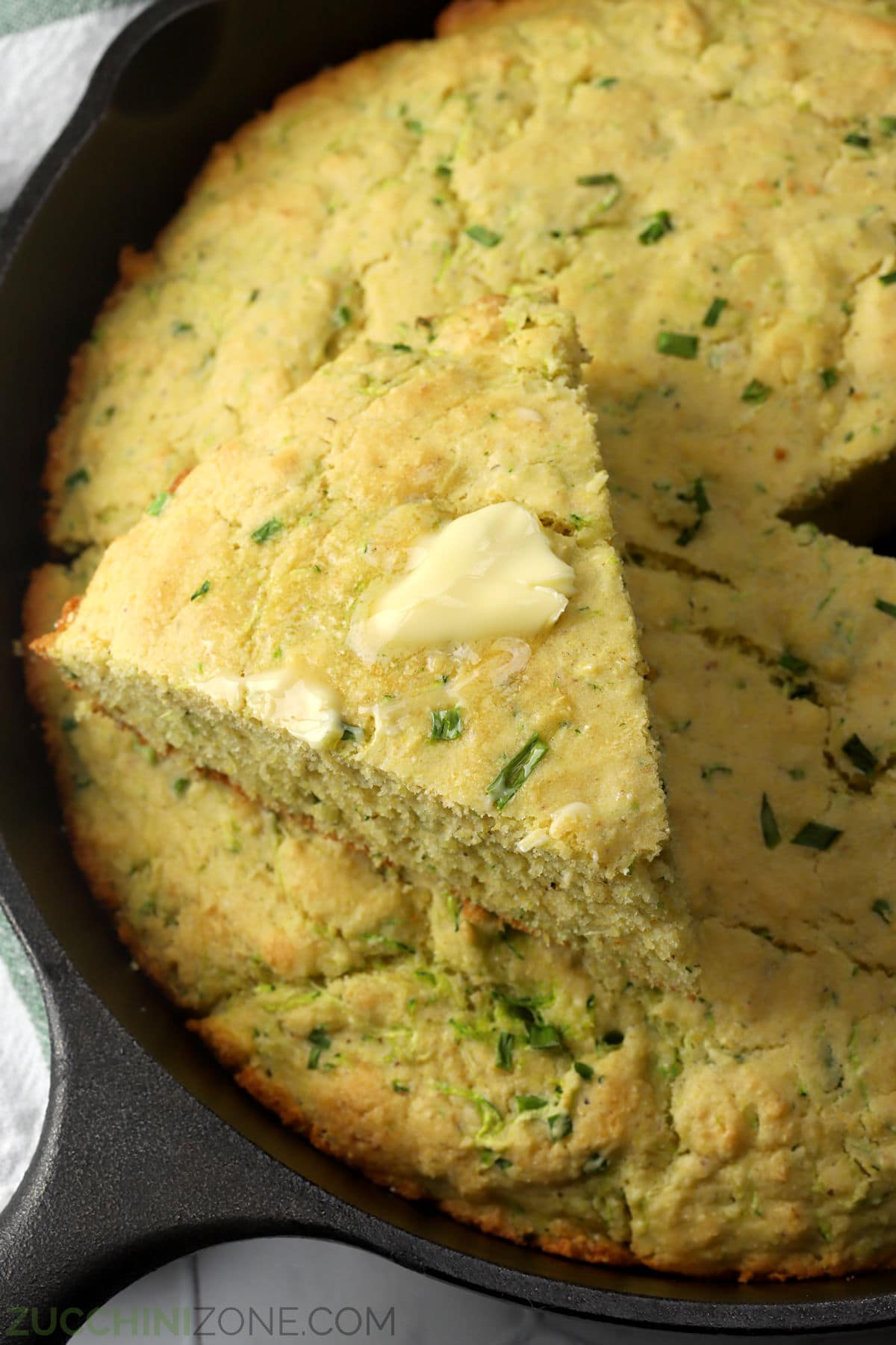 Wedge of zucchini cornbread topped with melting butter.