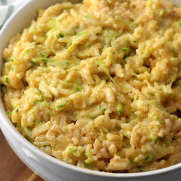 A bowl of cheesy rice with grated zucchini.