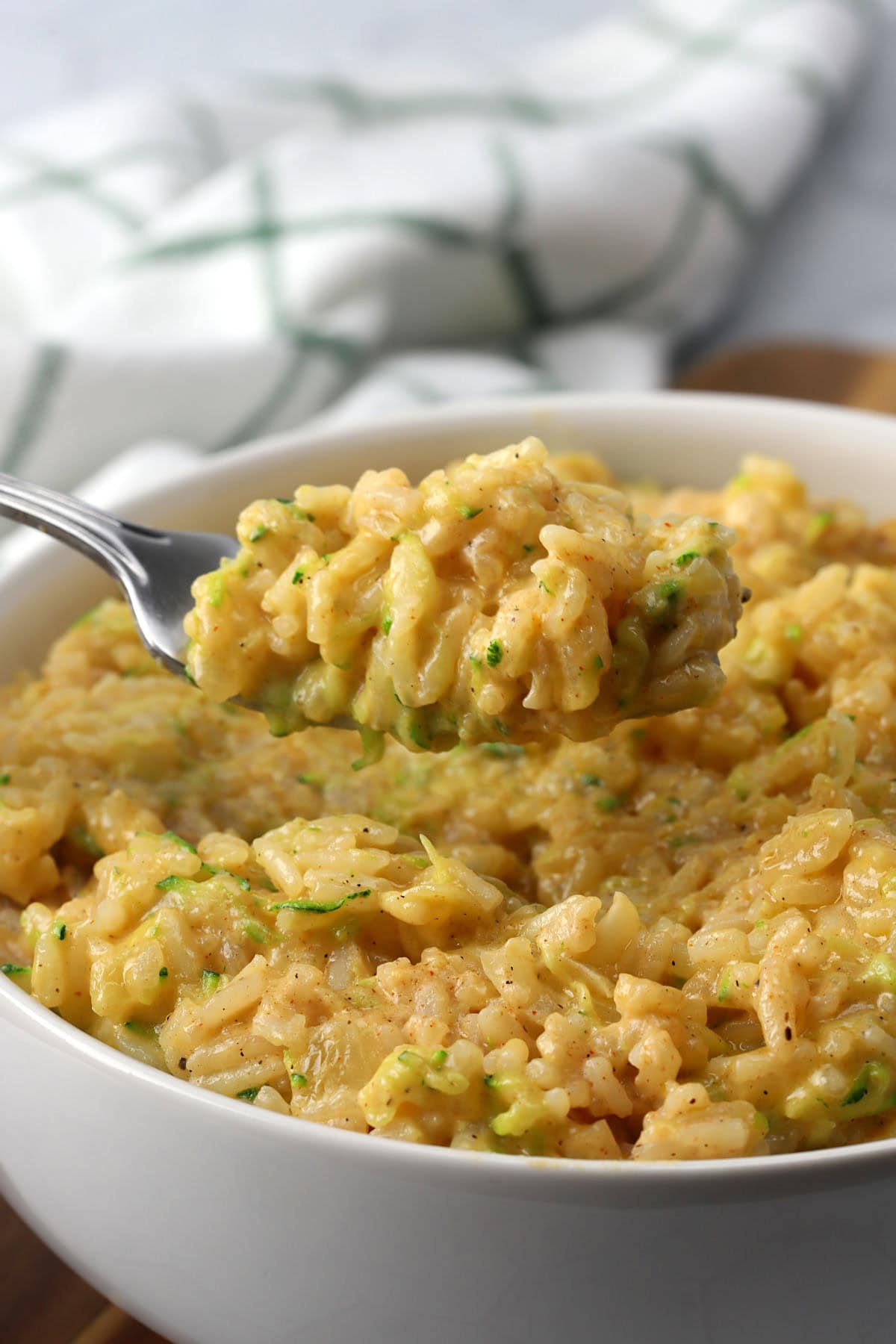 A bowl of cheesy rice with a metal fork.