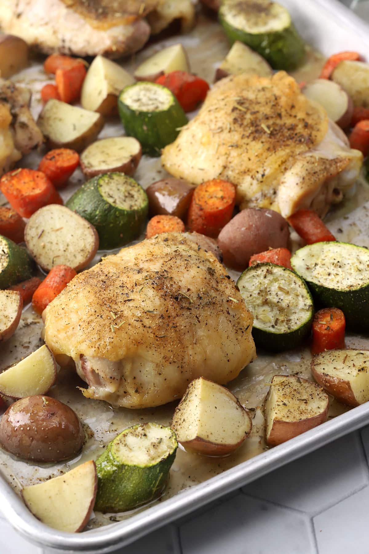 Roasted chicken thighs and vegetables on parchment.