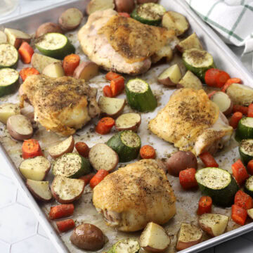 A sheet pan of chicken thighs with roasted vegetables.