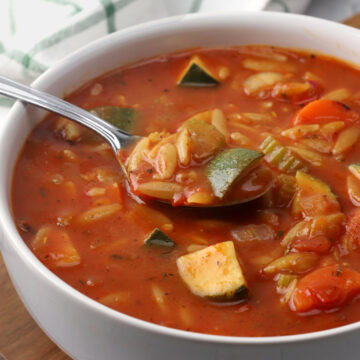A bowl of soup with a metal spoon.