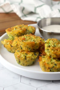 Cheesy zucchini bites stacked on a plate.