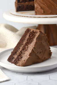 A slice of frosted chocolate cake on a plate.