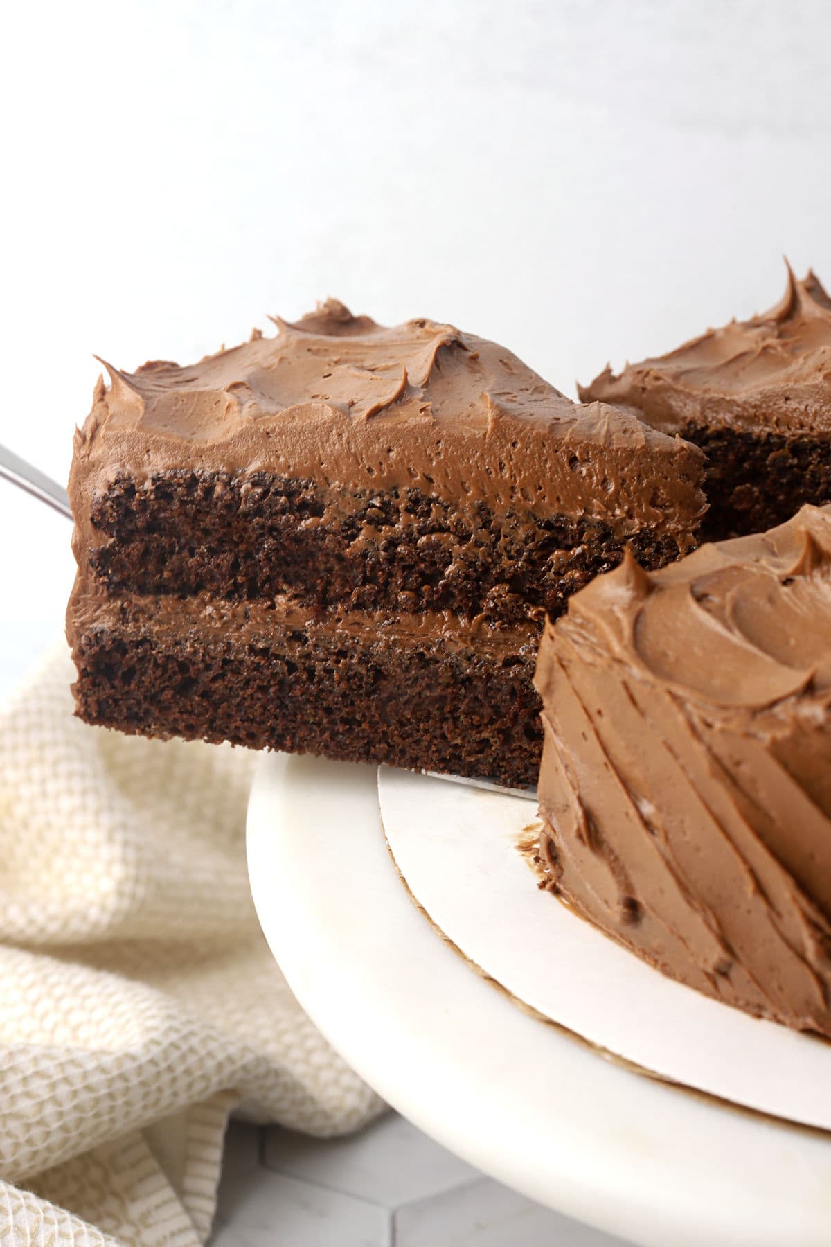 A slice of chocolate cake being pulled with a cake server.