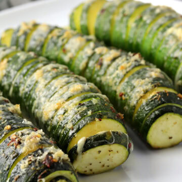 Partially sliced zucchini with cheese in the cracks.