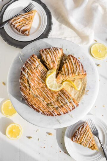 A lemon zucchini cake sliced and iced on a serving plate.