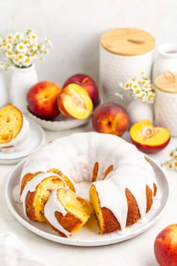 A sliced and iced bundt cake with peach garnish.